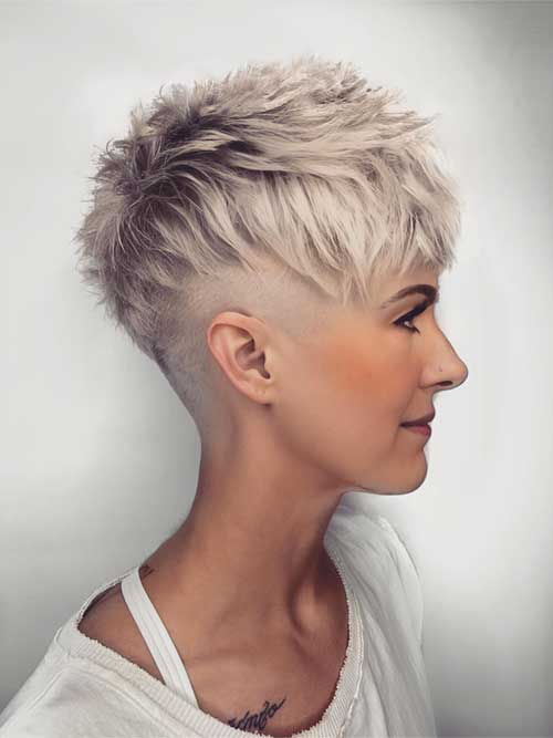 A woman with a short, edgy blonde pixie cut, showcasing her bold and stylish hairstyle with confidence.