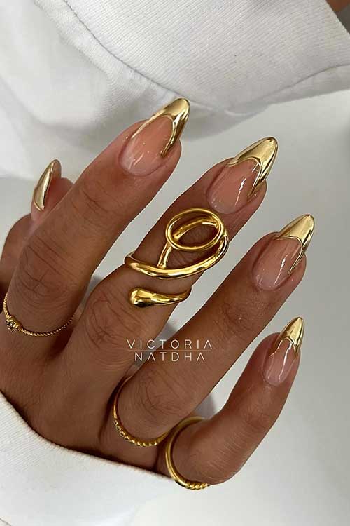 Long almond-shaped gold chrome French tip nails featuring a delicate 3D swirl design.