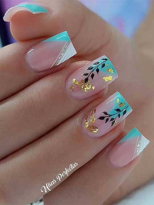 Short square shaped pastel blue and white two-tone V French tip nails with glitter, leaf nail art, and gold foil