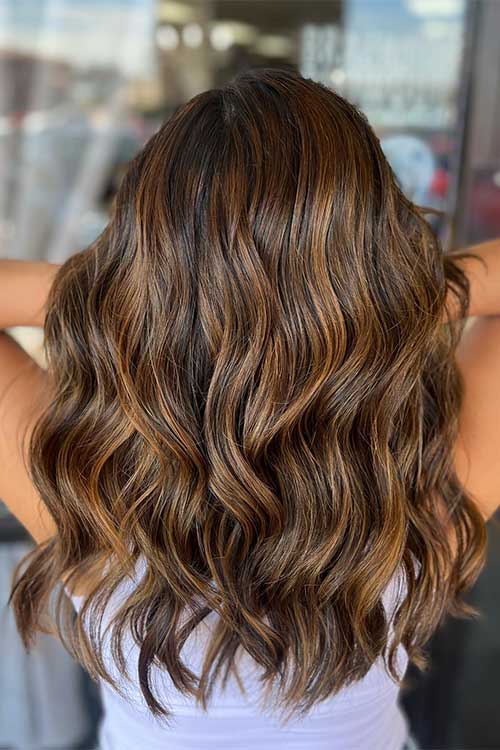 Long hair dyed with Cinnamon swirl hair color that is one of the trendy fall hair colors in 2023