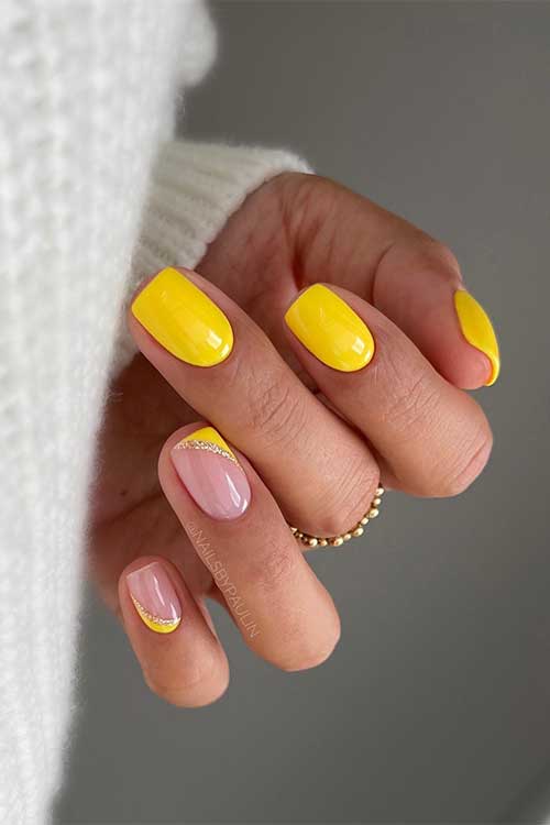 Short bright yellow nails with two accent diagonal and reverse diagonal French nails adorned with gold glitter
