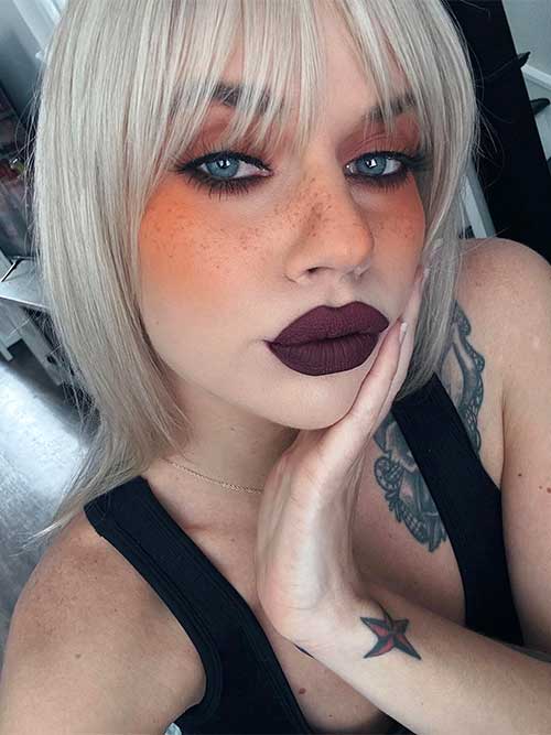 A pumpkin spice makeup look showcasing orange eyeshadow, smokey eyeliner, liquid orange blush, and rich plum matte lips.