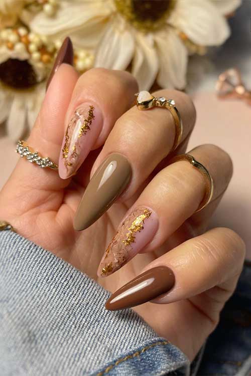 Long almond-shaped brown nails paired with chic nude pink accent nails embellished with shimmering gold flakes