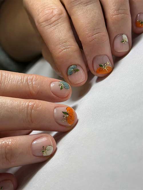 Short fall nails featuring green, white, and orange pumpkins on a nude base, accented with gold chrome details.