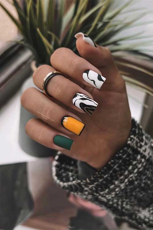Short square-shaped white and black abstract nails with a burnt yellow comic nail, and a matte dark green nail