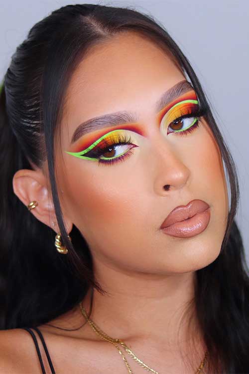 Smokey orange-yellow fall makeup look with neon green graphic liner and nude lips