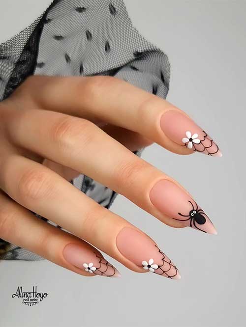 Cute Halloween nails featuring cobwebs, white flowers on tips, and a black spider on the middle nail.