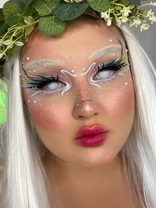 Fairy Halloween makeup features bleached eyebrows, white contact eyes, white pearls on the face, Voodoo Lashes, and red lips