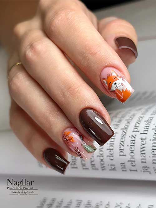 Chocolate brown Thanksgiving nails with a nude accent nail adorned with fall leaves and another accent with fox nail art.