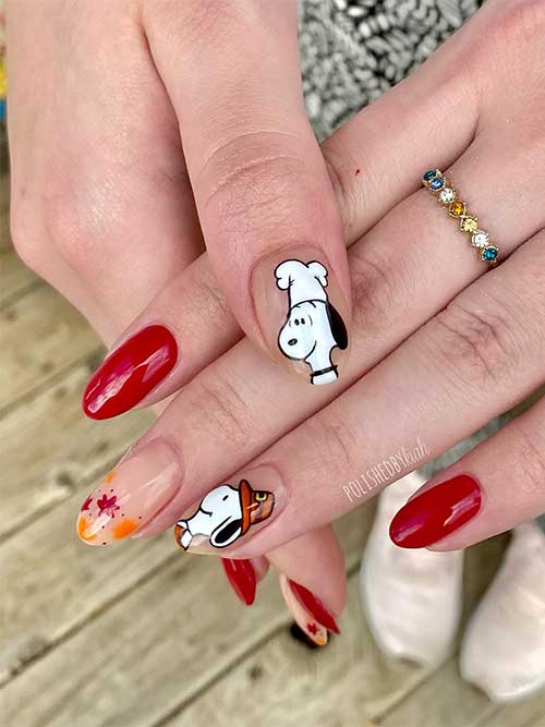 Red Thanksgiving nails with snoopy nail art on a nude accent nail and fall maple leaves on another nude accent nail