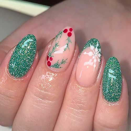 Almond-shaped glitter green Christmas nails with a nude accent nail adorned with holly nail art