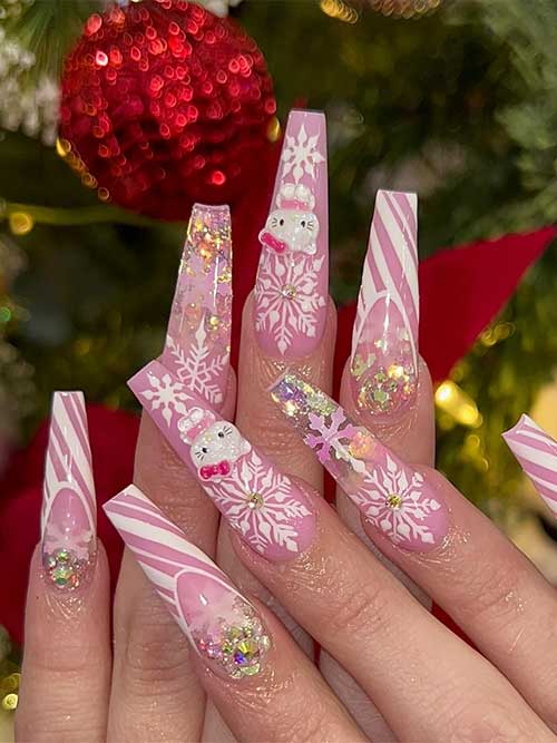 Long coffin pink Xmas nails with candy nail art, snowflakes, glitter, rhinestones, and a 3D Hello Kitty nail art