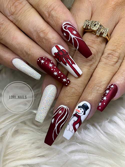 Long dark red and white Christmas nails with icicle nail art, a snowman, a gift tie nail art, and a white glitter accent nail
