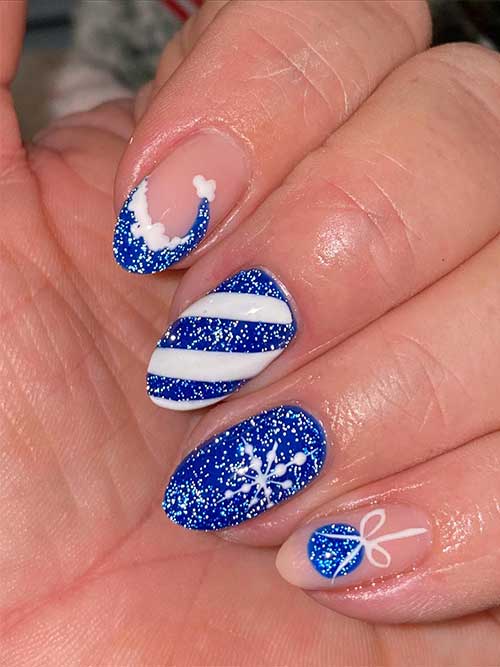 Short glitter blue Christmas nails feature a candy cane, a gift ball, a snowflake, and a Santa hat nail art