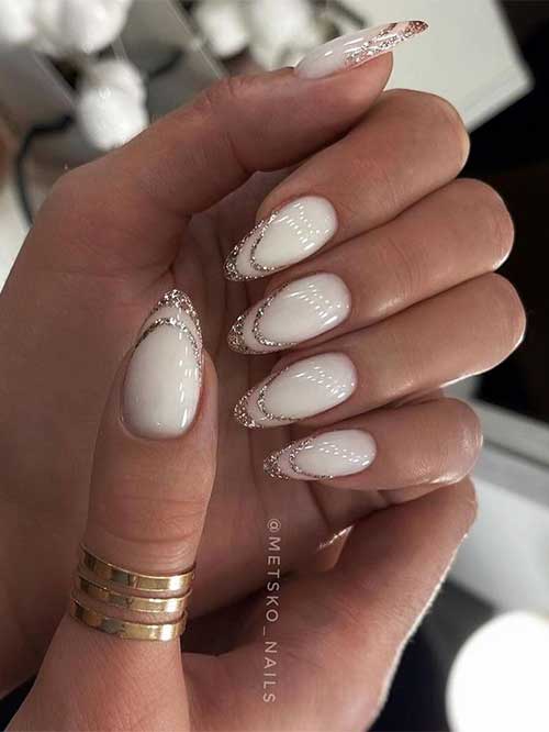 Almond-shaped negative space festive French manicure adorned with rose gold glitter tips over a milky white base color