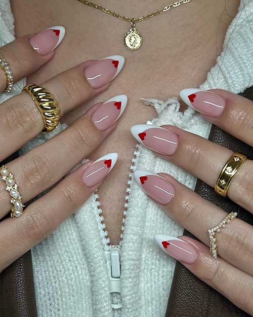 Cute almond-shaped white French Valentine's Day nails adorned with a red heart shape on the nail tip
