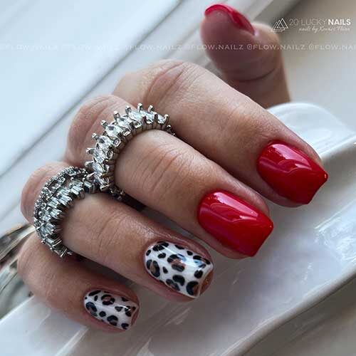 Glossy short red Valentine’s Day nails with two accent brown and black leopard nails over white nail base color