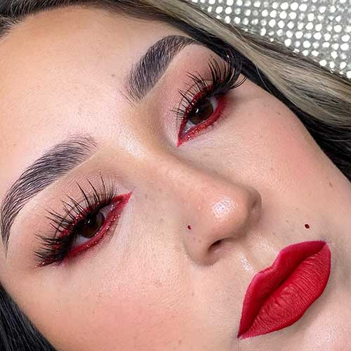 Gorgeous Valentine’s makeup look features long lashes, red glitter eyeliner, and matte red lips