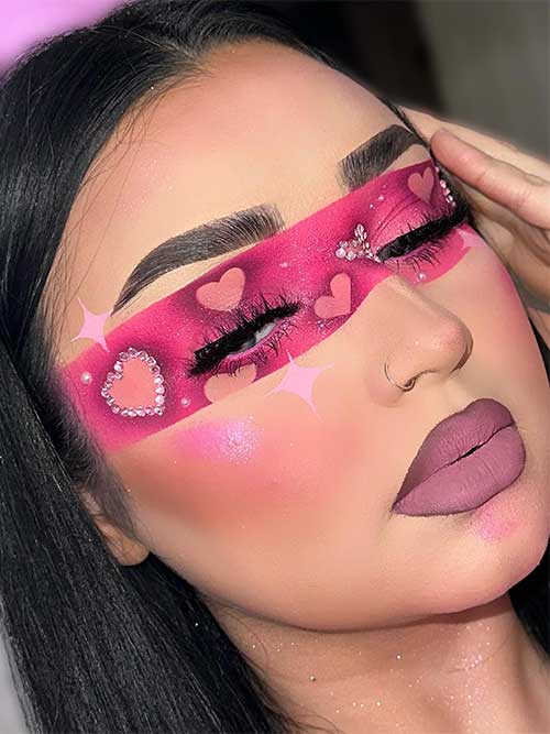 Hot Pink Valentine's Day eye mask makeup look adorned with nude pink heart shapes some of them adorned with crystals