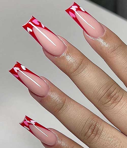 Long classic red French Valentine’s Day nails are adorned with white and pink heart shapes
