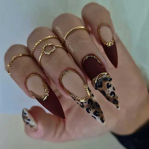 Long stiletto Matte leopard nails with two burgundy accent French nails and the design is adorned with gold decorations