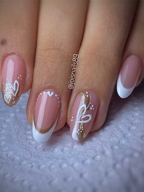 Medium almond-shaped white French nails with a gold glitter French accent, white heart shapes, and swirl nail art on accent
