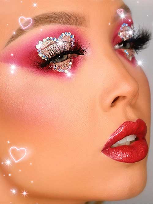 Red-winged eyeshadow look with a gold glitter big heart on the eye adorned with a crystal outline, long lashes, and red lips