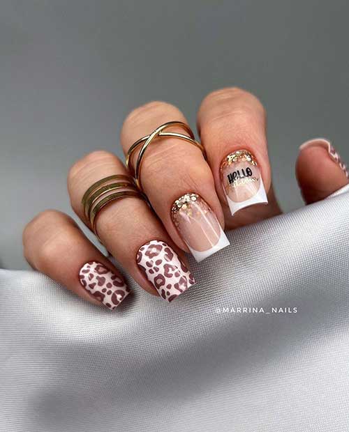 Short white nails with brown leopard prints and two accent white French tips adorned with gold glitter above the cuticles