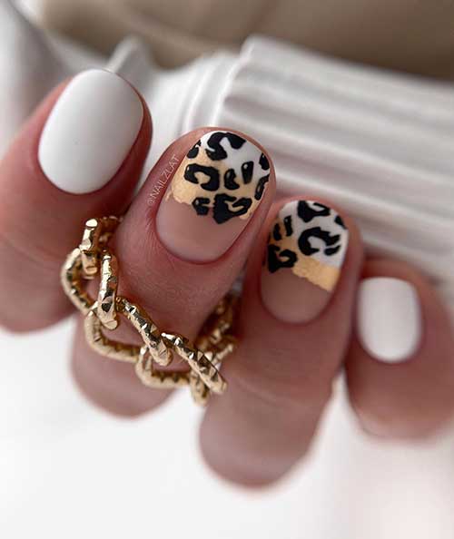 Short white nails with two accent black leopard print nails over abstract nail art with white, peach, and nude nail colors