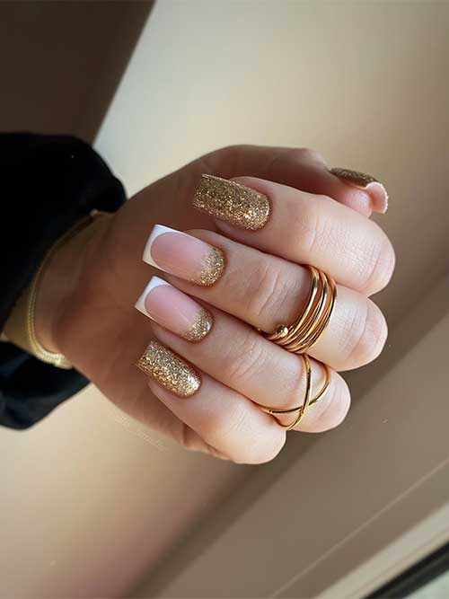 Sparkling gold glitter nails with two accent white French tip nails adorned with gold glitter above the cuticle