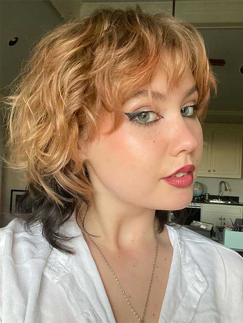 Stunning two-toned short shaggy mullet haircut features honey blonde hair with black back hair strands