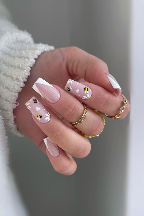 Cute white V French nails with two accent matte nude nails with white daisy flowers, dots, and hearts