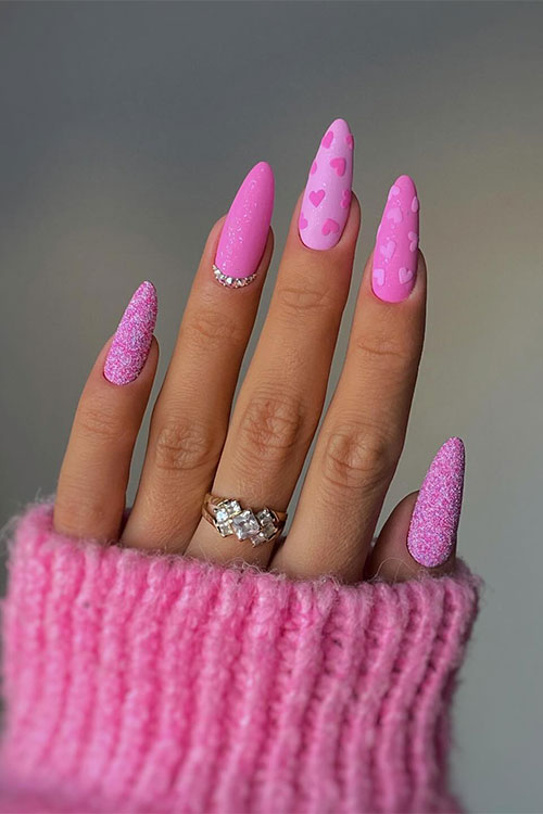 Glittery different shades of pink Valentine's Day nails with two accent matte pink nails adorned with heart shapes
