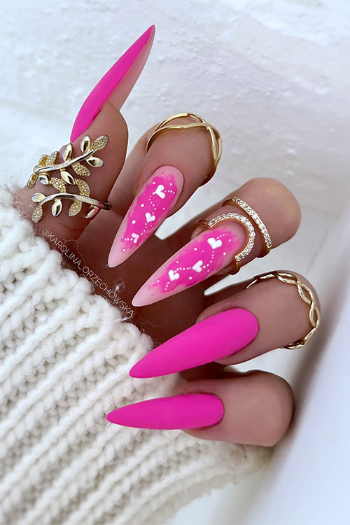 Gorgeous long stiletto-shaped matte pink Valentine’s Day nails with hot pink abstract nail art with white hearts and dots