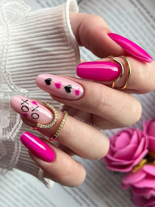 Hot pink Valentine’s Day nails with two accent nude pink nails adorned with black and hot pink hearts and XO nail art designs