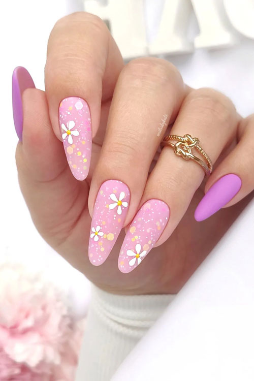 Matte pink and purple spring nails feature light nude pink nails with daisy flowers and white dots and two light purple nails