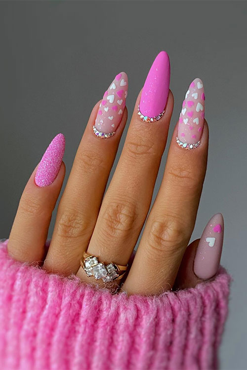 Nude and pink Valentine’s nails feature a pink nail with sugar glitter and another matte pink nail with silver rhinestones
