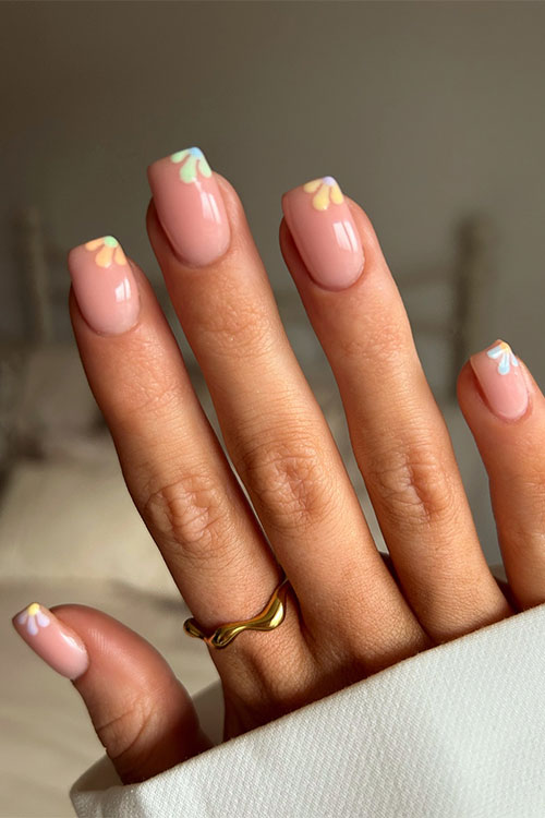 Simple spring nail design features multicolored diagonal flower French tips over a nude base color