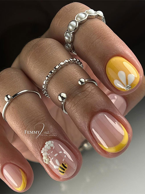 Yellow short spring nails feature two French accent nails and a nude accent nail adorned with bee and daisy flowers