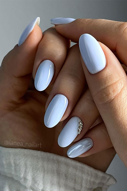 Long almond-shaped baby blue nails with an accent adorned with silver rhinestones and a chrome accent nail