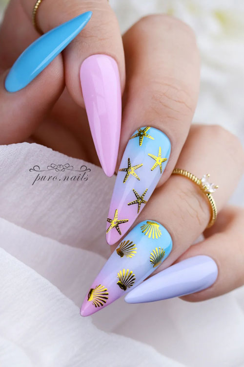 Long almond-shaped pink, purple, and blue nails adorned with two ombre accent nails adorned with gold seashells and sea stars