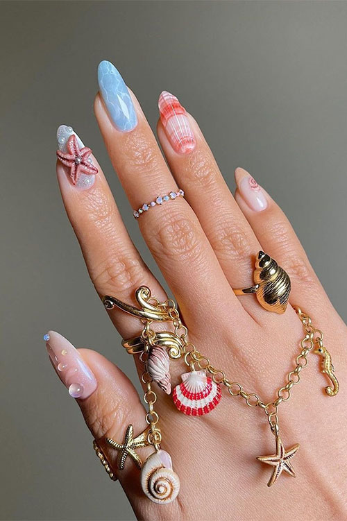 Long almond-shaped underwater nails adorned with seashells, sea stars, and pearl accents
