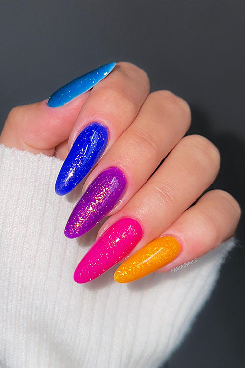 Long bold multicolored nails summer almond shaped that feature pink, yellow, violet, blue, and marine nail colors with glitter