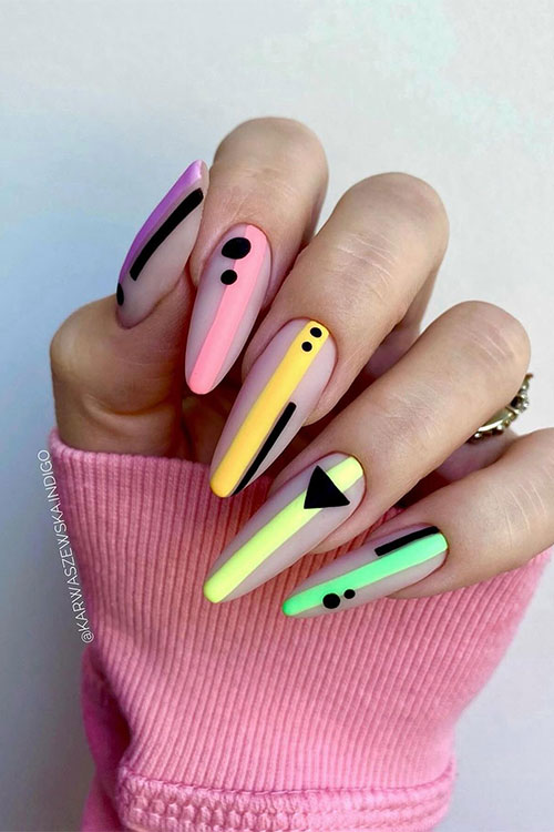 Long matte geometric wide centerlines multicolored nails over a nude base color and adorned with black geometric symbols