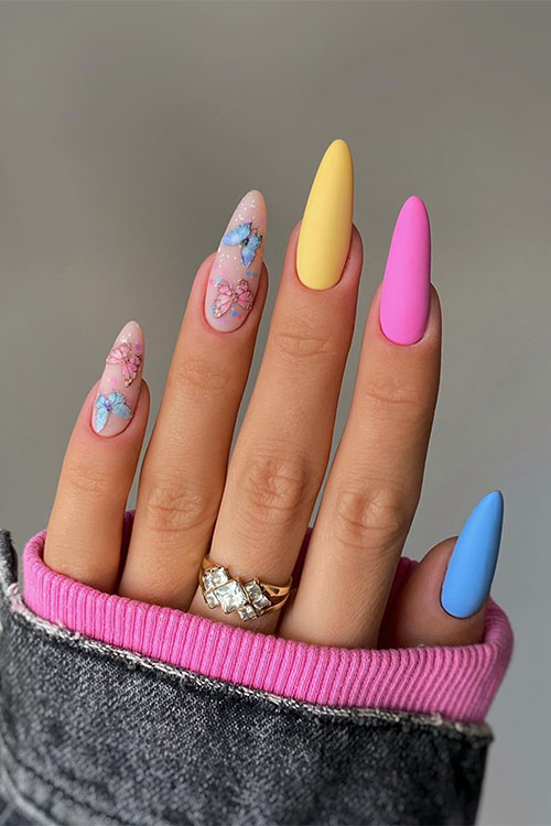 Long matte yellow pink and blue nails almond shaped with two accent nude nails adorned with blue and pink butterflies