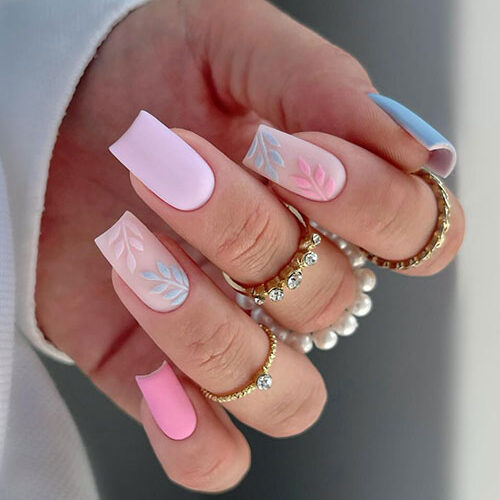 Long square-shaped blue, pink, and lilac matte pastel nails with two accent nude nails adorned with leaf nail art