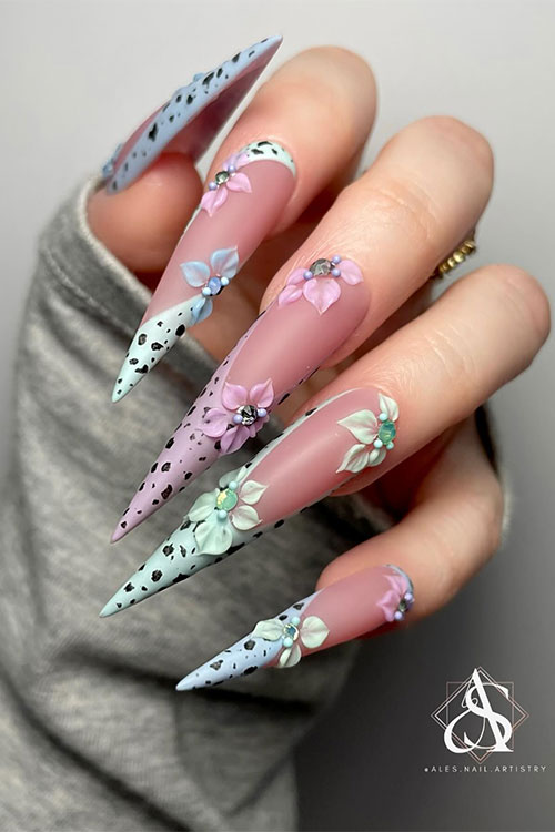 Long stiletto-shaped pastel blue, green, and mauve French egg easter nails adorned with flowers