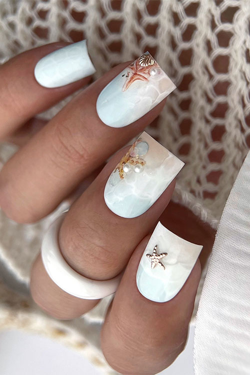 Matte light aqua nails with water effect and beach nail art on the tips adorned with sea shells, seastars, and pearls