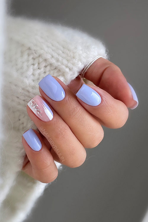 Short blue purple pastel nails with a nude accent nail adorned with white, glitter, and blue-purple abstract nail art