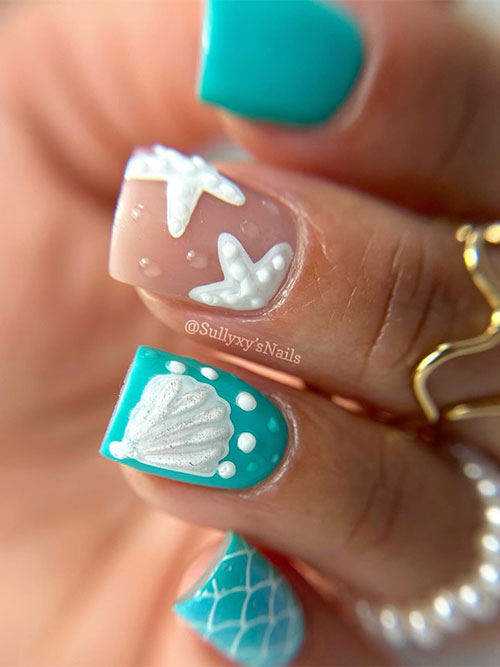 Short turquoise nails adorned with a white seashell on an accent nail, sea stars, water droplets, and mermaid accent nail